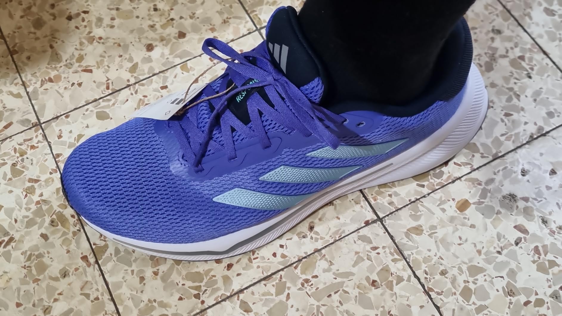 Adidas Response running shoe side profile showing mesh construction and three stripes design