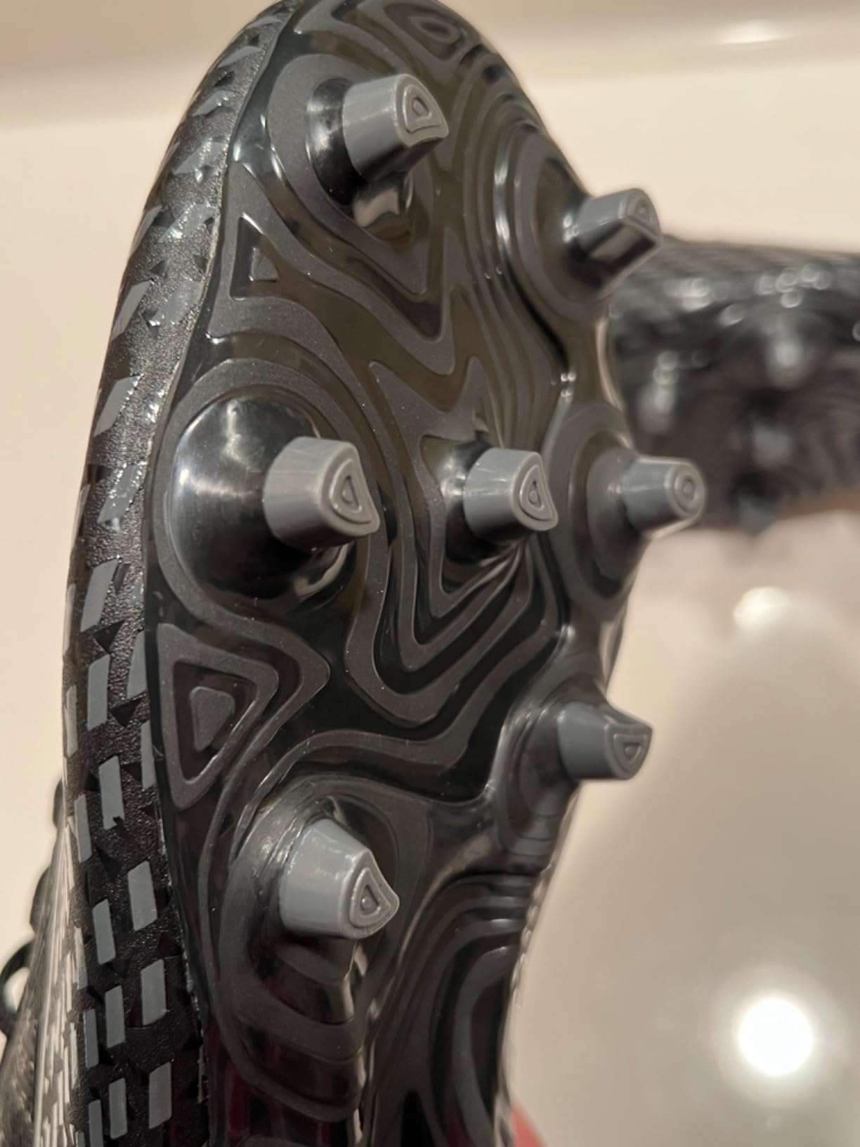 LEOCI soccer cleats in black-grey colorway showing synthetic upper and molded conical cleat pattern