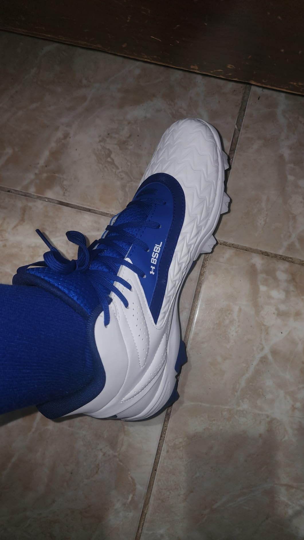 Under Armour Leadoff Mid 3.0 baseball cleats on diamond field showing rubber molded cleat configuration and traction pattern