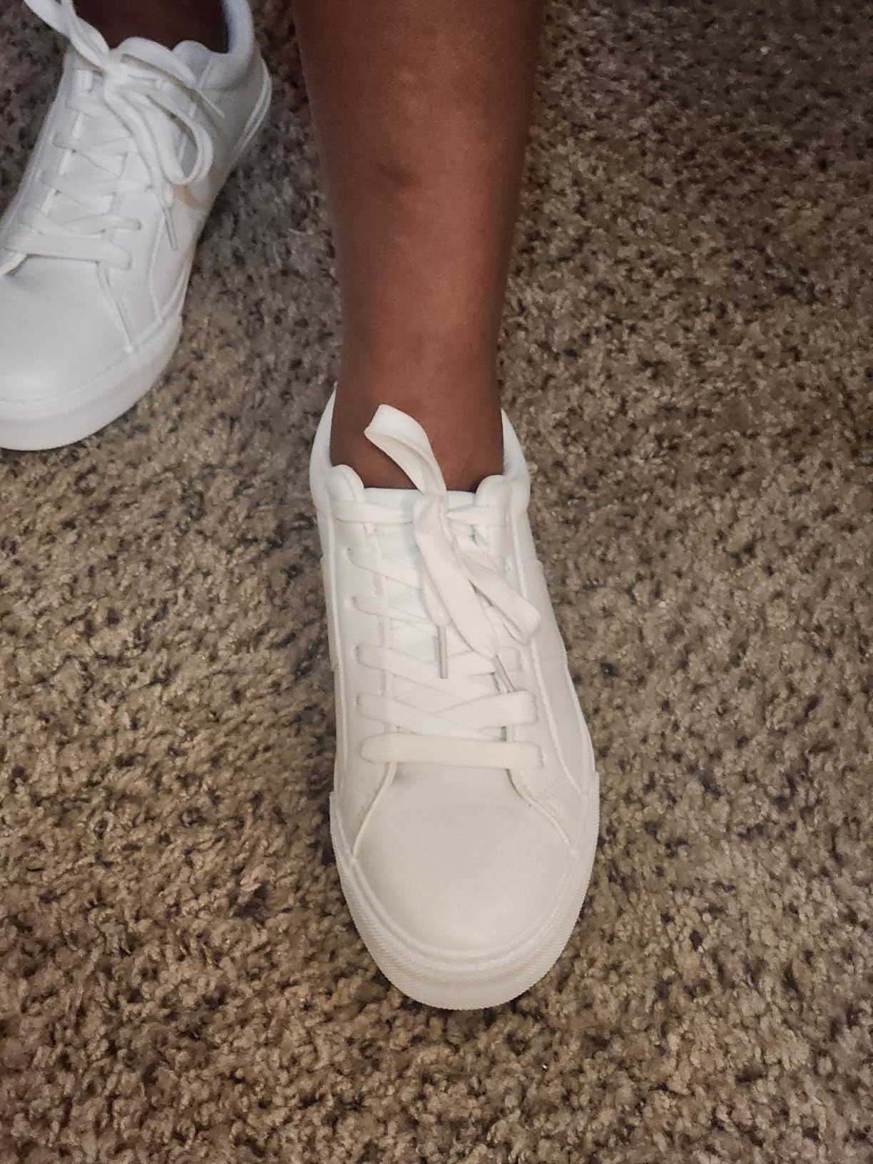 Close-up detail of Adokoo sneaker showing white PU leather material and stitching quality