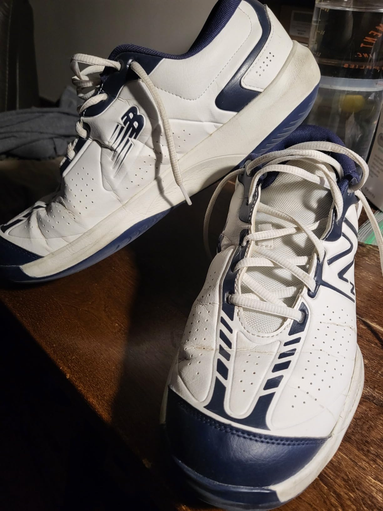 New Balance Men's 696 V5 tennis shoe in white and blue colorway showing herringbone outsole and court-specific design