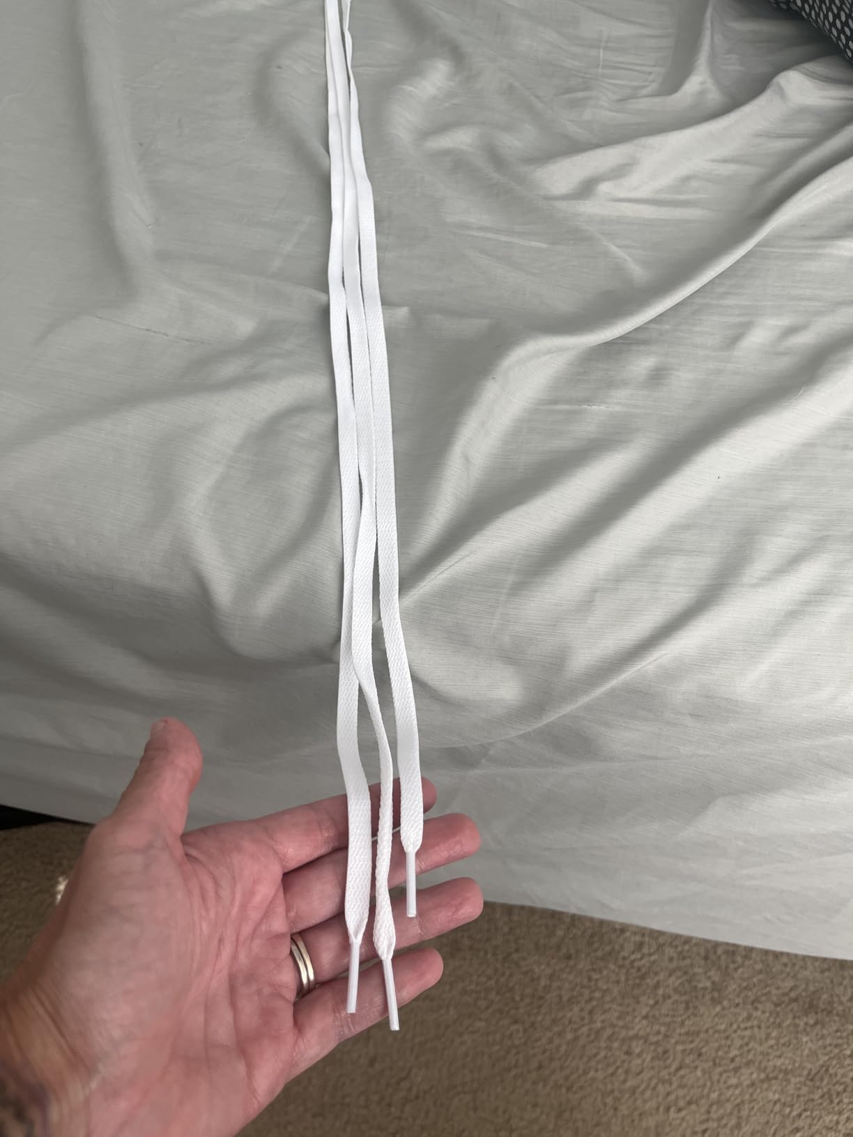 Close-up of UpUGo flat shoelace material showing texture, aglet construction, and bright white color