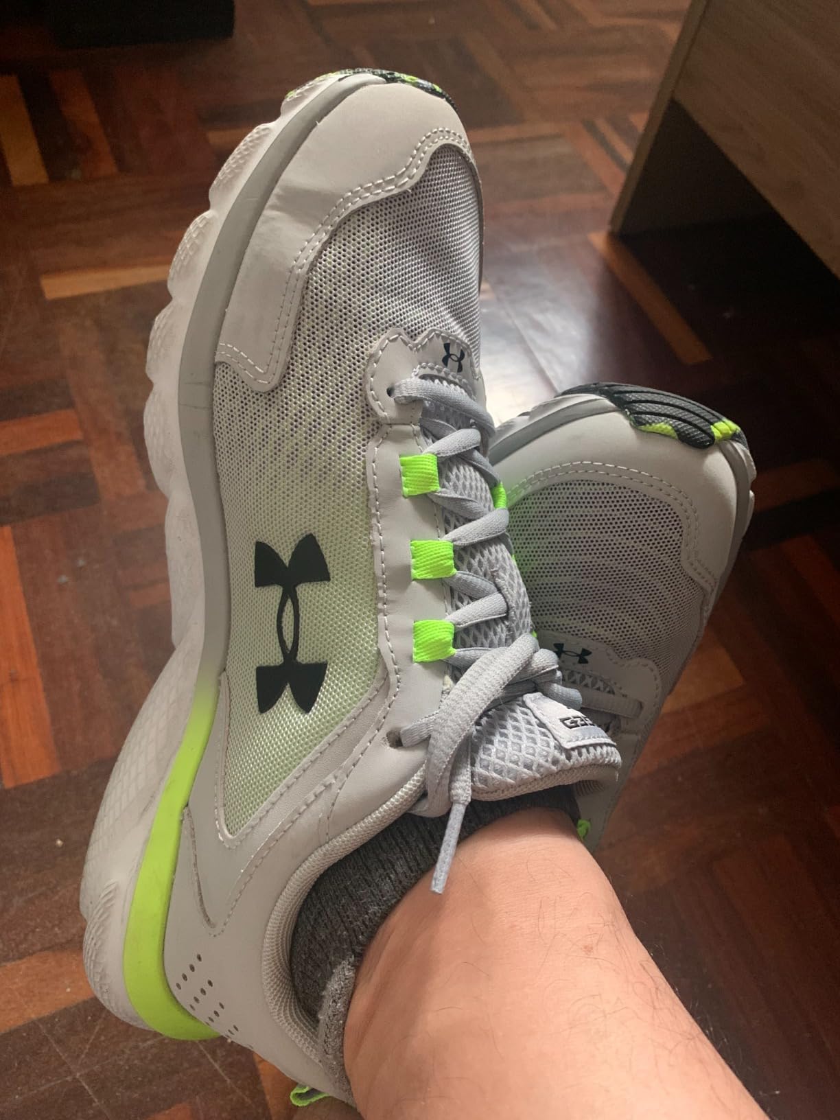 Under Armour Charged Assert 9 in black and blaze orange colorway showing lightweight mesh upper with leather overlays and Charged Cushioning midsole technology
