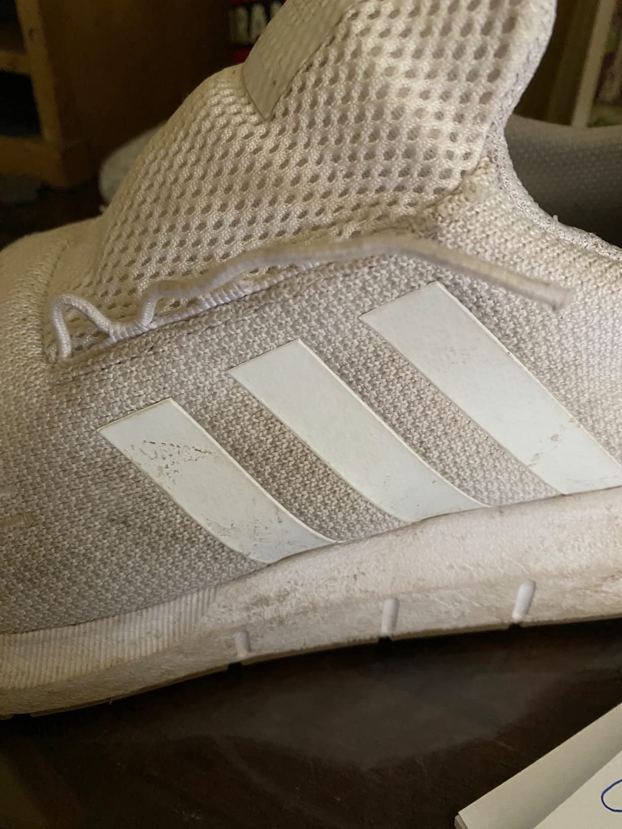 Macro close-up of failed Adidas Swift Run lace eyelet showing pulled-out fabric loop from knit upper
