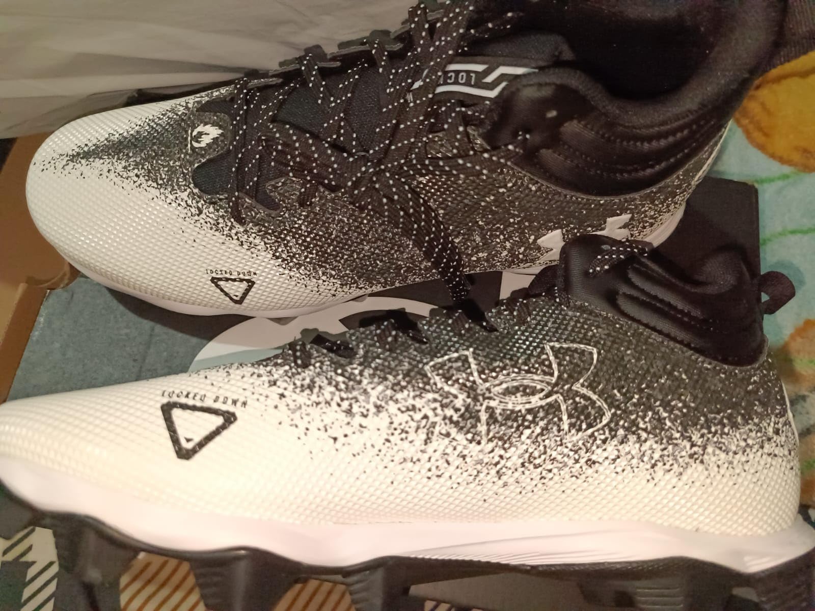 Under Armour Spotlight Fran 2.0 football cleats in black colorway showing 5/8 inch mid-cut ankle design and molded rubber cleat pattern