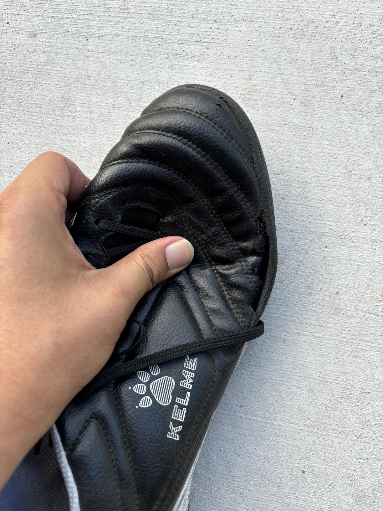 Close-up of KELME cleat showing side material construction and early wear patterns at upper-to-sole junction after 6 weeks of testing