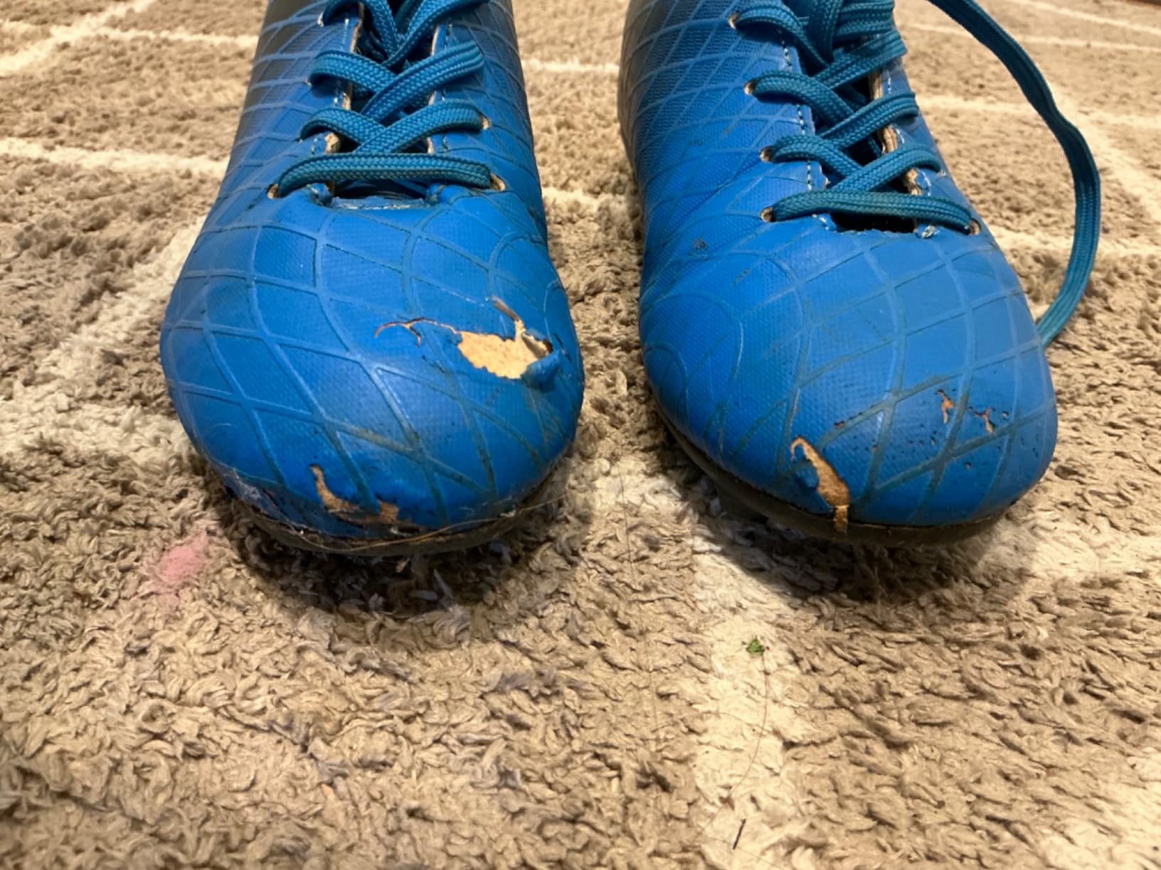 Damaged kids soccer cleats after a few practices showing outsole separation and wear
