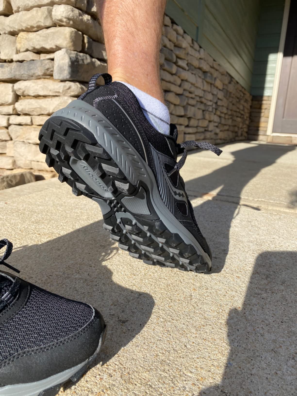 Saucony TR16 action shot during trail running on mixed wet terrain showing flexibility and natural ground contact